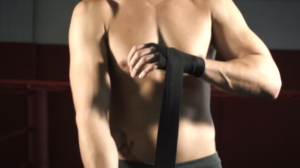 Мужчина боксер тянет бинты на руки — стоковое видео