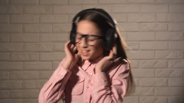 Девушка-подросток в наушниках слушает музыку — стоковое видео