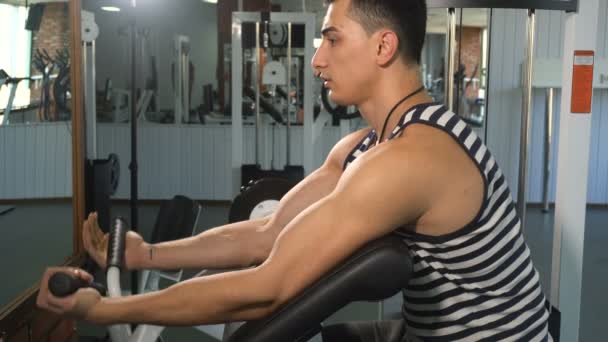 Mocny człowiek robi ćwiczenia w maszynie biceps — Wideo stockowe