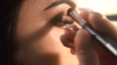 Makyaj sanatçısı kadın modeli için makyaj yapar