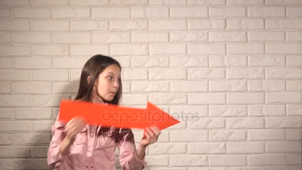 Adolescente chica en rosa camisa mostrar algo por flecha roja — Vídeos de Stock