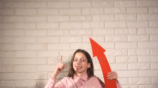 Дівчина-підліток в рожевій сорочці показує щось червоною стрілкою — стокове відео