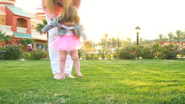 Niña haciendo los primeros pasos con las madres ayudan — Vídeo de stock