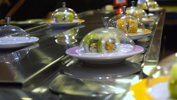 Блюда суши и сашими катятся по конвейерной ленте — стоковое видео