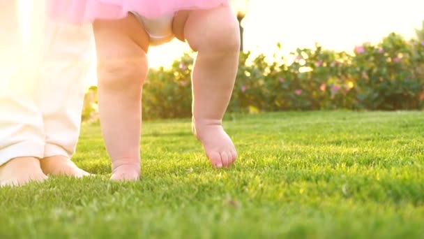 Niña haciendo los primeros pasos con las madres ayudan — Vídeo de stock