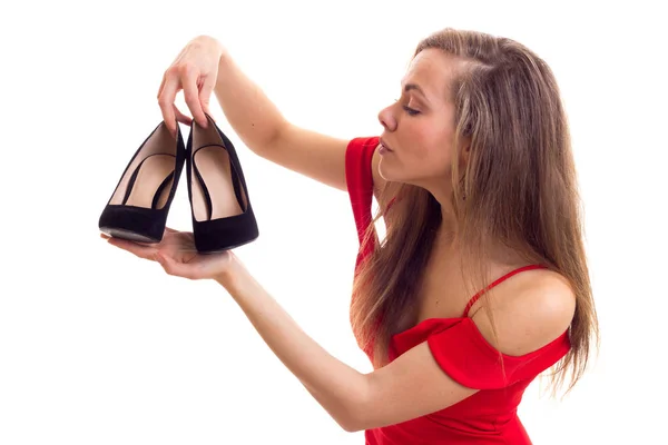 Jonge vrouw in rode jurk houden van schoenen — Stockfoto