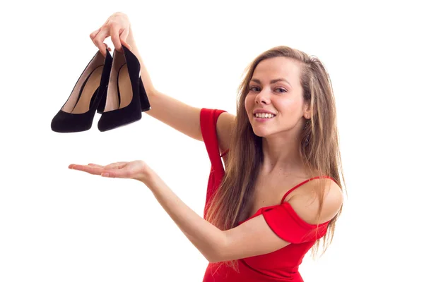 Mujer joven en vestido rojo sosteniendo zapatos —  Fotos de Stock