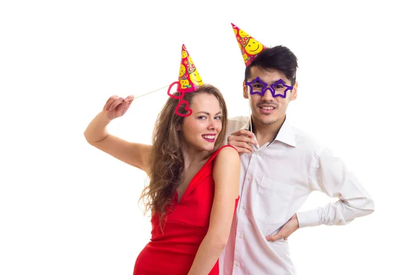 Young couple with card sticks and celebrating hats — Stock Photo, Image