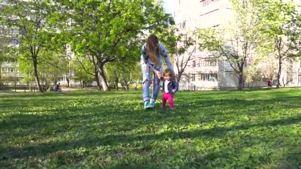 Madre enseñando a su bebé los primeros pasos cerca de casa — Vídeos de Stock