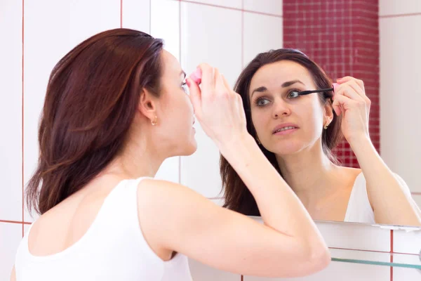 Jeune femme utilisant mascara dans la salle de bain — Photo