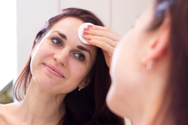 Mujer joven quitando el maquillaje en el baño — Foto de Stock