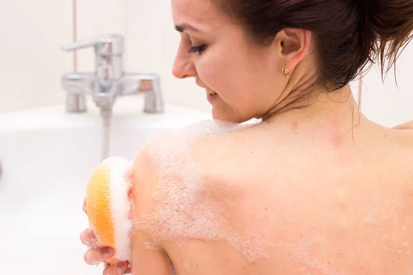 Jeune femme lavant avec une éponge dans le bain — Photo