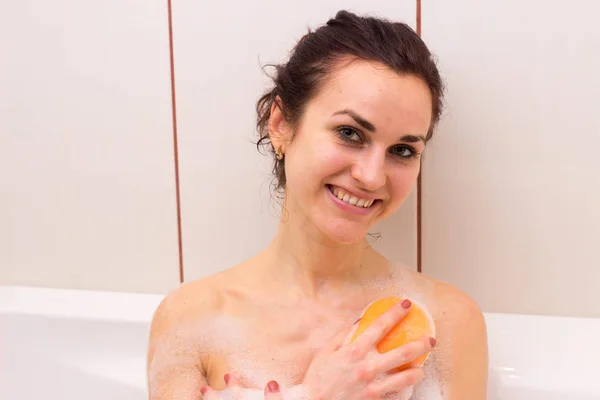 Jovem mulher lavando com esponja no banho — Fotografia de Stock