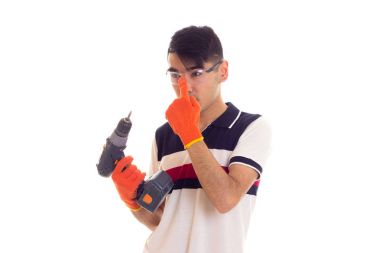 Eldiven ve gözlük elektrikli tornavida tutan genç adamla