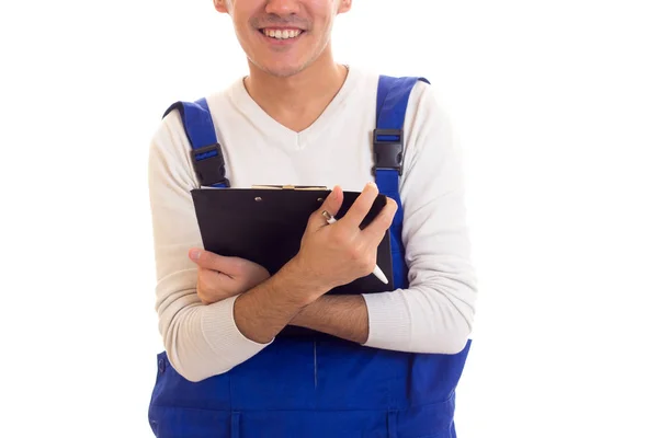 Young man in blue overall holding pen and folder — Stock Photo, Image