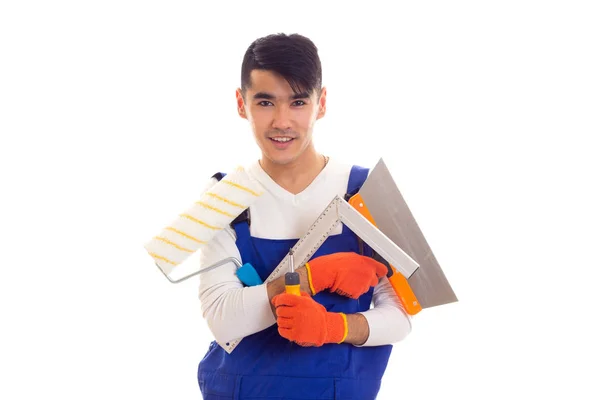 Людина в цілому з рукавичками тримає шпатель, рулон, лінійку і викрутку — стокове фото