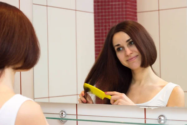 Ung kvinna borsta håret i badrummet — Stockfoto