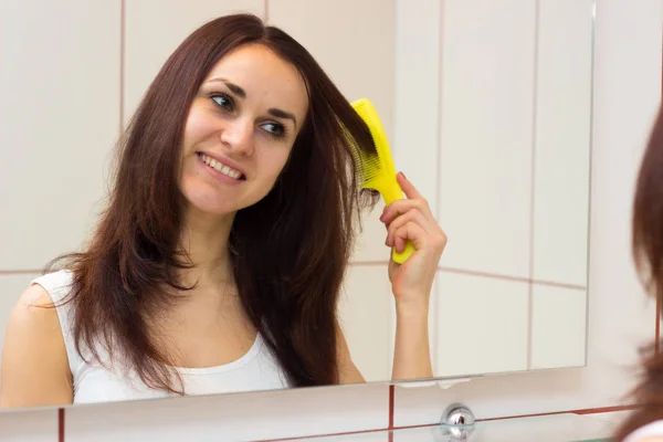 Jovem escovar o cabelo no banheiro — Fotografia de Stock