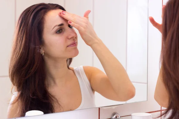 Młoda kobieta przy użyciu krem do twarzy w łazience — Zdjęcie stockowe