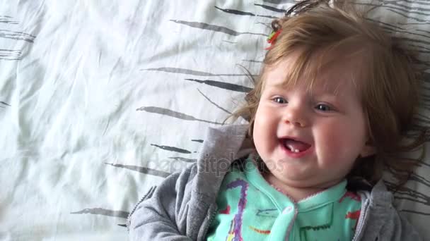 Мила дівчинка посміхається лежачи на ліжку — стокове відео