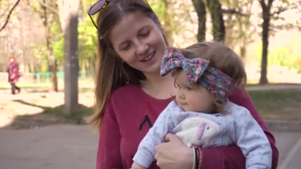 Мати гуляє з дівчинкою в парку — стокове відео