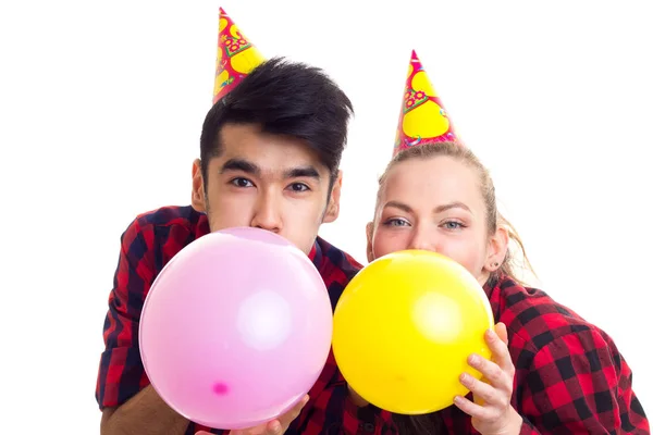 Joven pareja soplando globos — Foto de Stock