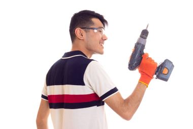 Eldiven ve gözlük elektrikli tornavida tutan genç adamla