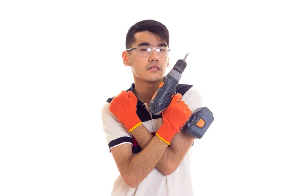 Молодой человек в перчатках и очках держит электрическую отвертку — стоковое фото
