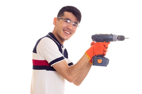 Joven con guantes y gafas sujetando destornillador eléctrico — Foto de Stock