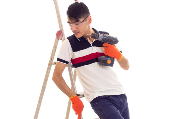 Jonge man houden van elektrische schroevendraaier en zittend op de ledder — Stockfoto