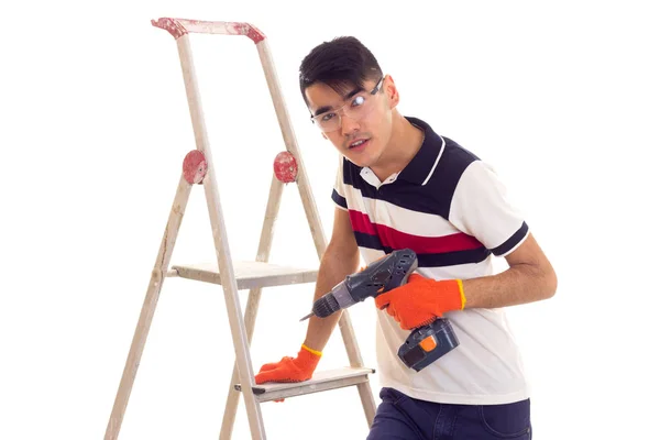 Jonge man houden van elektrische schroevendraaier en zittend op de ledder — Stockfoto