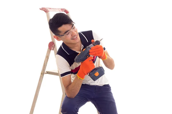 Young man holding electric screwdriver and sitting on ledder — Stock Photo, Image