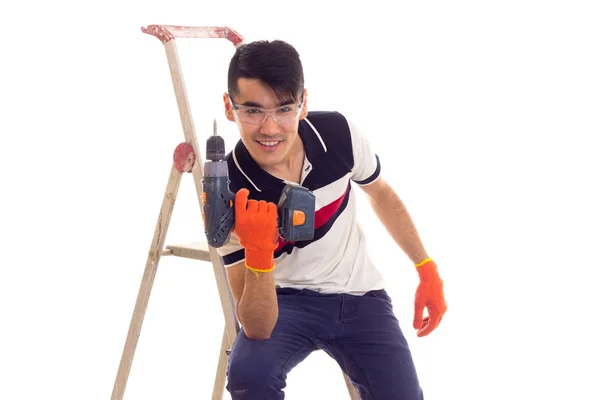 Jonge man houden van elektrische schroevendraaier en zittend op de ledder — Stockfoto