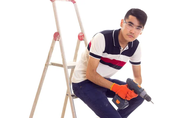 Jovem segurando chave de fenda elétrica e sentado no livro — Fotografia de Stock