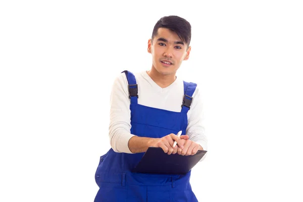 Young man in blue overall holding pen and folder — Stock Photo, Image