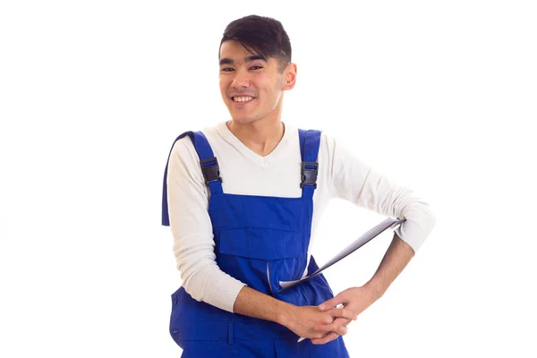 Young man in blue overall holding pen and folder — Stock Photo, Image
