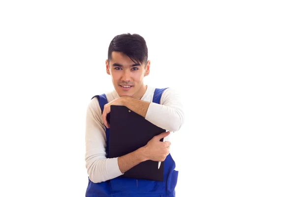 Young man in blue overall holding pen and folder — Stock Photo, Image