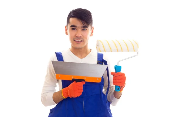 Mann in blauem Overall mit Handschuhen, die Spachtel und Rolle halten — Stockfoto