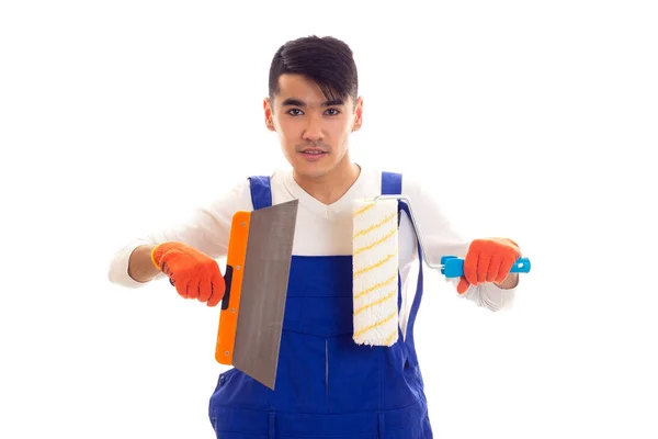 Mann in blauem Overall mit Handschuhen, die Spachtel und Rolle halten — Stockfoto