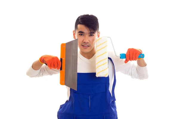 Мужчина в синем в целом с перчатками, держащими лопатку и рулон — стоковое фото