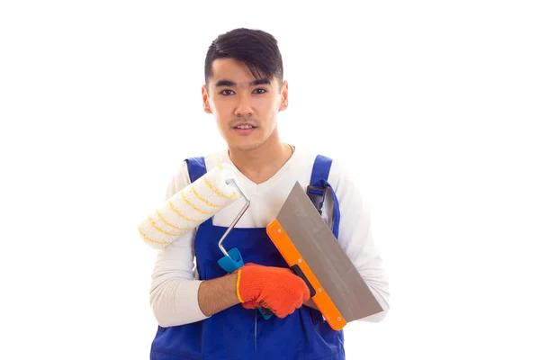Ο άνθρωπος σε μπλε συνολικά με γάντια κρατώντας σπάτουλα και ρολό — Φωτογραφία Αρχείου
