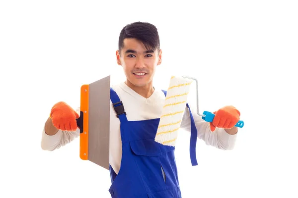 Mann in blauem Overall mit Handschuhen, die Spachtel und Rolle halten — Stockfoto