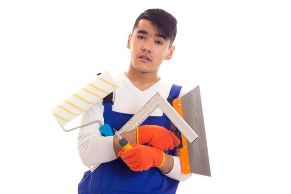 Homem em geral com luvas segurando espátula, rolo, régua e chave de fenda — Fotografia de Stock