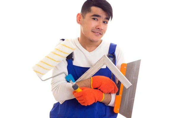 Man in overall met handschoenen spatel, roll, liniaal en schroevendraaier — Stockfoto