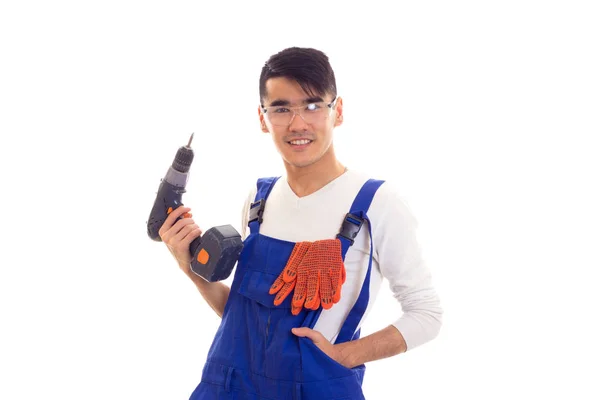 Mann im Overall mit Handschuhen und Brille hält Elektroschrauber in der Hand — Stockfoto