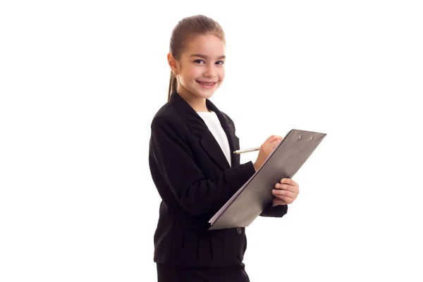 Klein meisje in zwarte jas holding pen en map — Stockfoto
