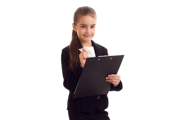 Little girl in black jacket holding pen and folder — Stock Photo, Image