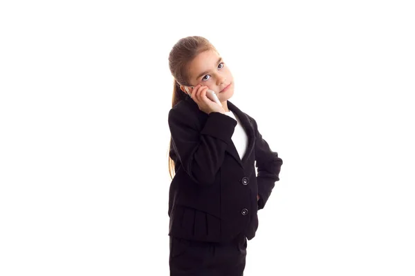 Маленькая девочка в черной куртке разговаривает по телефону — стоковое фото
