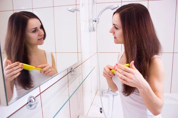 Genç bir kadın banyoda saçını tarıyor. — Stok fotoğraf