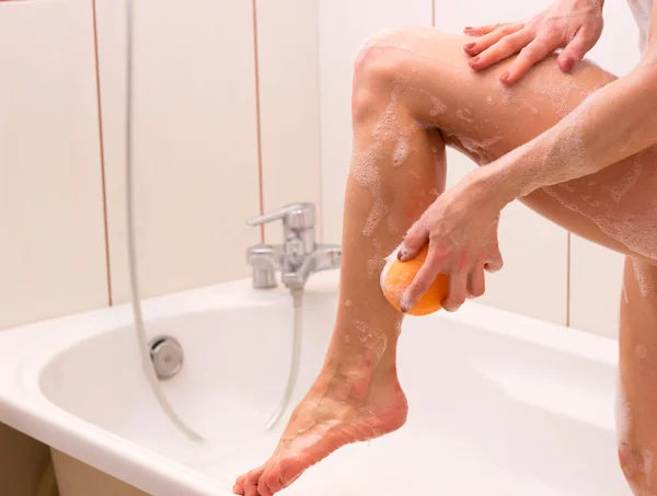 Giovane donna che si lava con la spugna nel bagno — Foto Stock